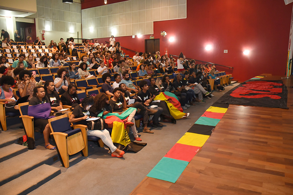 Foto da plateia do auditório da Faculdade de Ciências Médicas que mostra participação de movimentos sociais 