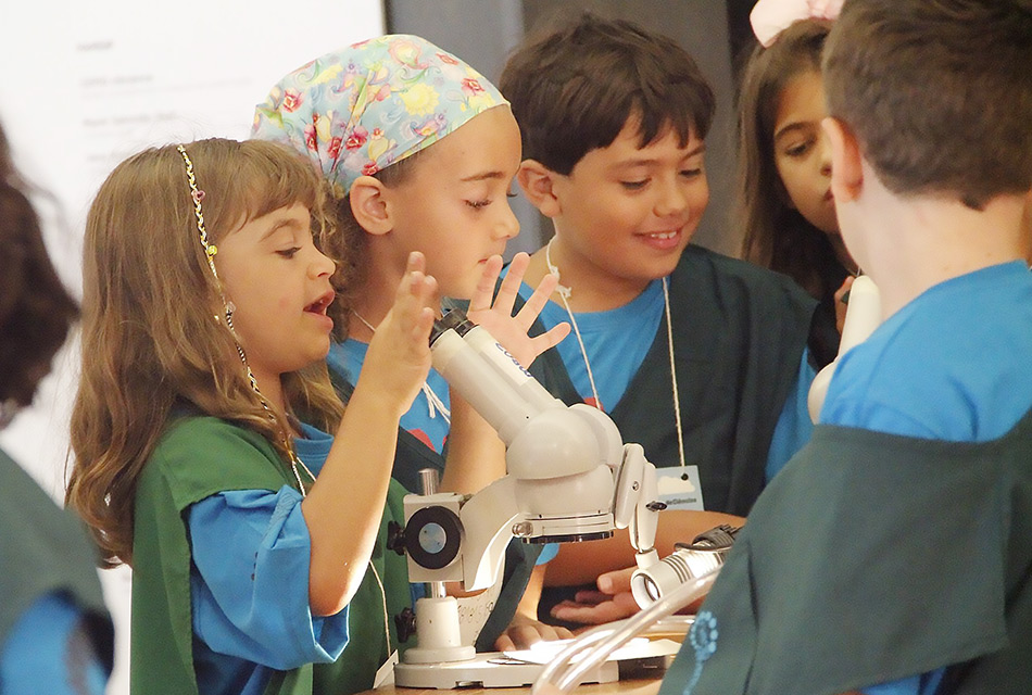 Participantes do Férias no Museu usam microscópio durante oficina