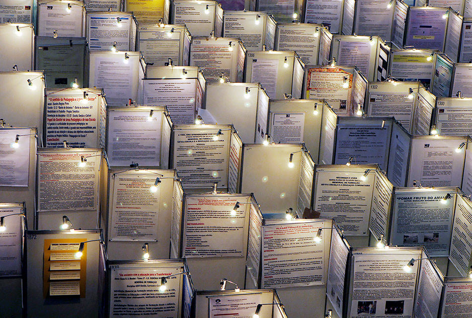 Vários posteres iluminados em foto de congresso de iniciação científica