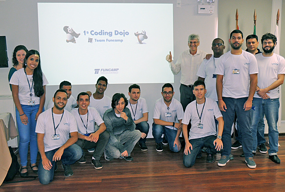 Equipes completas posam para foto na frente do cartaz do evento