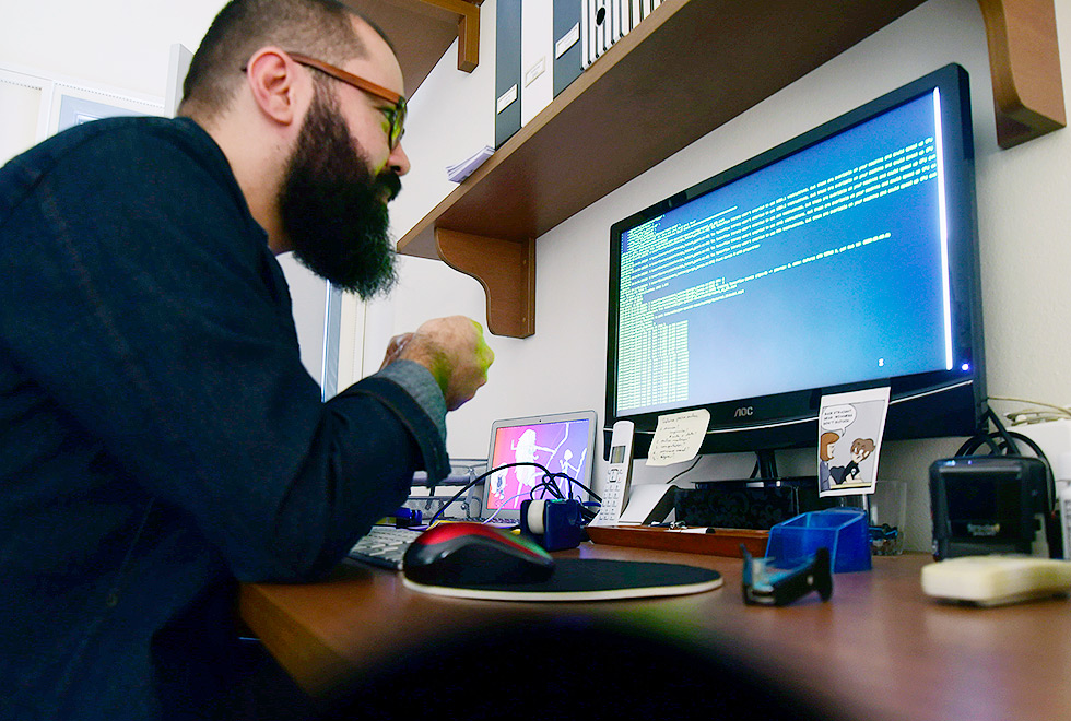 home de barba e óculos olha tela de computador