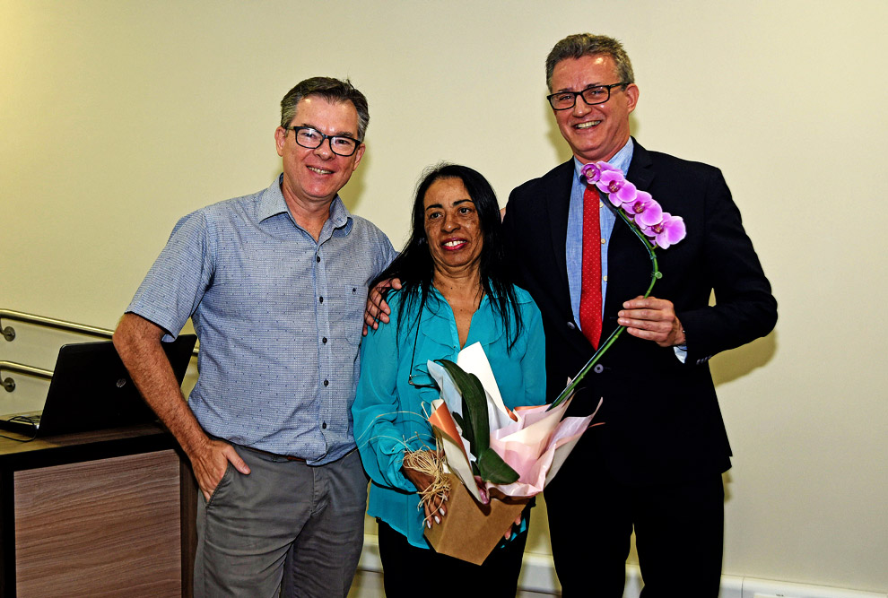 Cícera de Souza Almeida recebe flores dos diretores Antonio José de Almeida Meirelles e Flávio Schmidt Diretores e funcionária posam para foto
