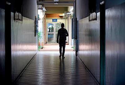 Imagem mostra um longo corredor com um aluno andando