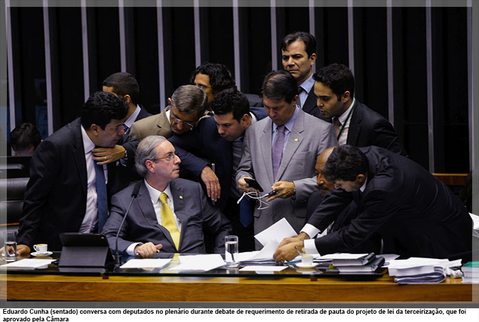 Eduardo Cunha (sentado) conversa com deputados no plenário durante debate de requerimento de retirada de pauta do projeto de lei da terceirização, que foi aprovado pela Câmara