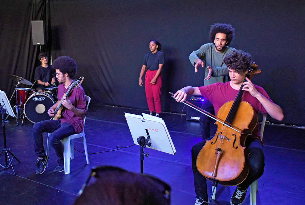 Trecho do espetáculo do projeto Sala Muda, dois bailarinos fazem movimentos junto aos músicos