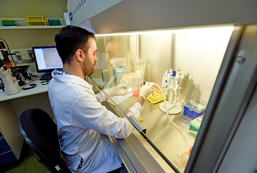 foto mostra rapaz em laboratório trabalhando com instrumentos científicos. ele veste jaleco branco