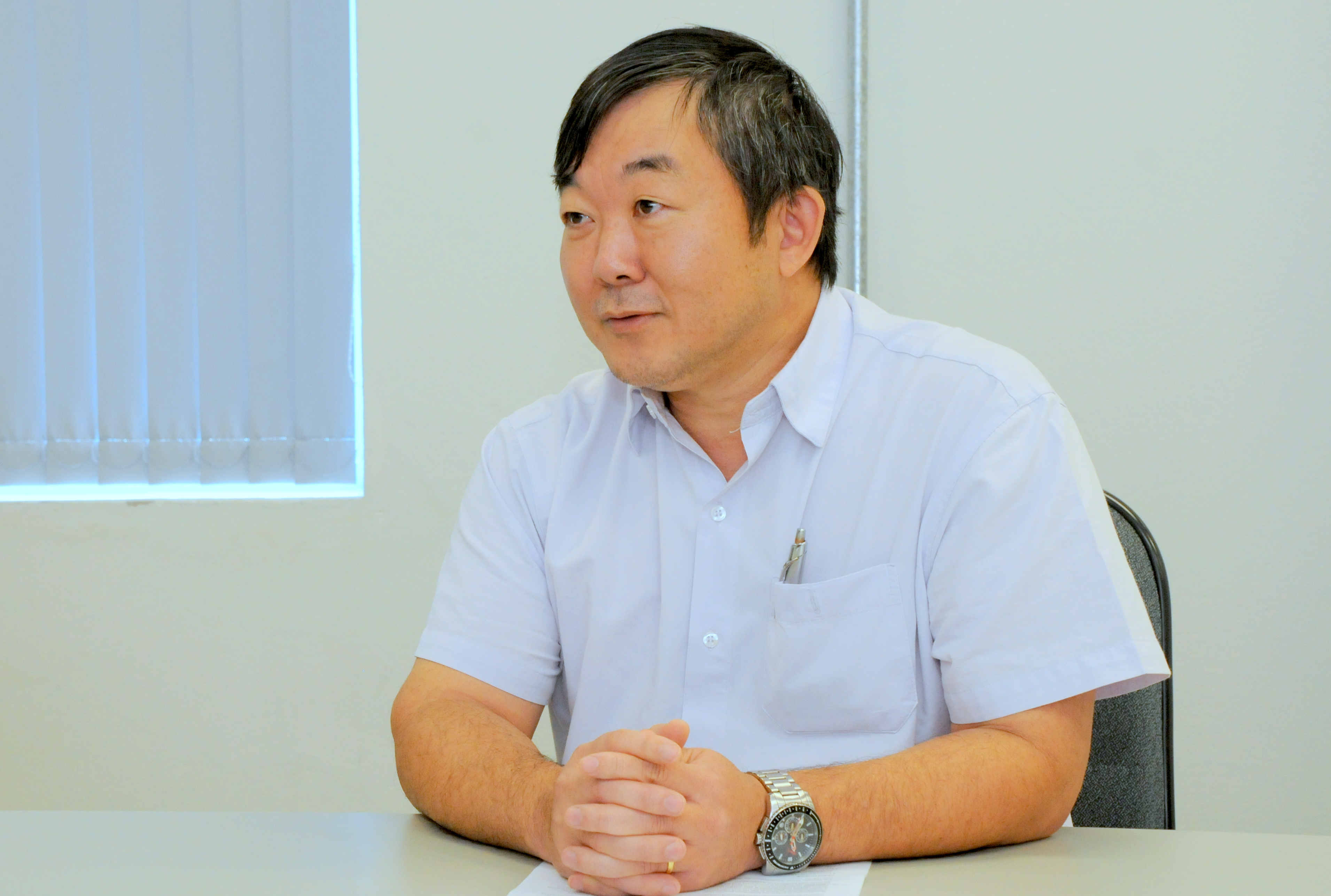 foto mostra professor lauro kubota sentado à mesa, vestindo camisa azul