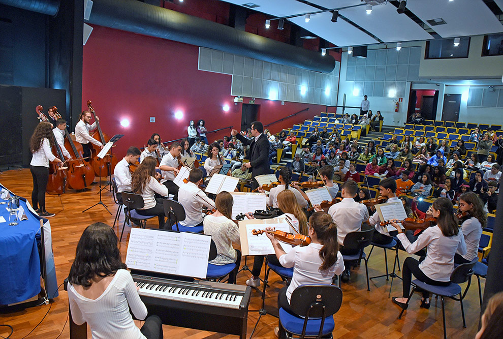 Jovens músicos da camerata de corda se apresentam no palco do auditório da FCM