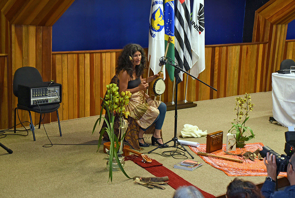 mulher sentada em cadeira com instrumentos musicais canta