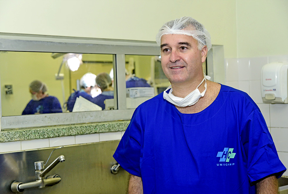 Gustavo Fraga veste indumentária do centro cirúrgico, aparece em pé, da cintura para cima