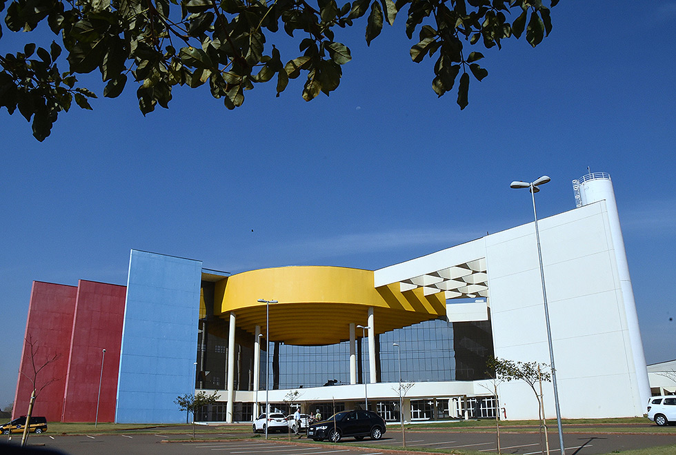 Fachada do hospital regional com carros estacionados à frente. O prédio tem detalhes em amarelo vermelho e azul