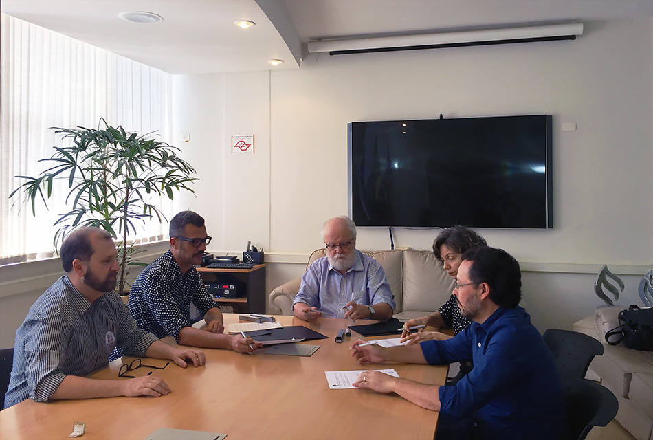 Cinco pessoas reunidas em volta da mesa no Gabinete do reitor José Tadeu, entre eles Gustavo Ciríaco.