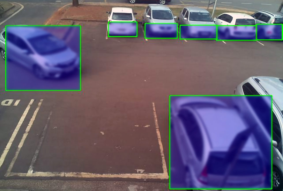 Foto mostra como sistema enxerga os carros no estacionamento, fazendo a detecção das vagas. Os carros aparecem atrás de uma tela azul.