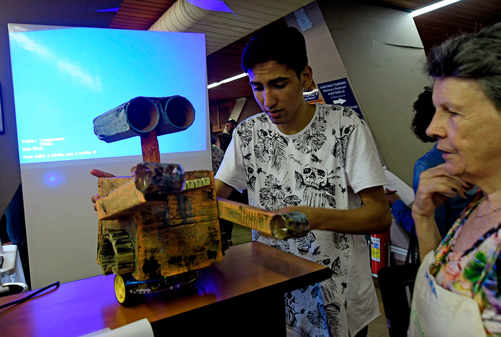 Mateus mostra o robô para uma visitante da exposição