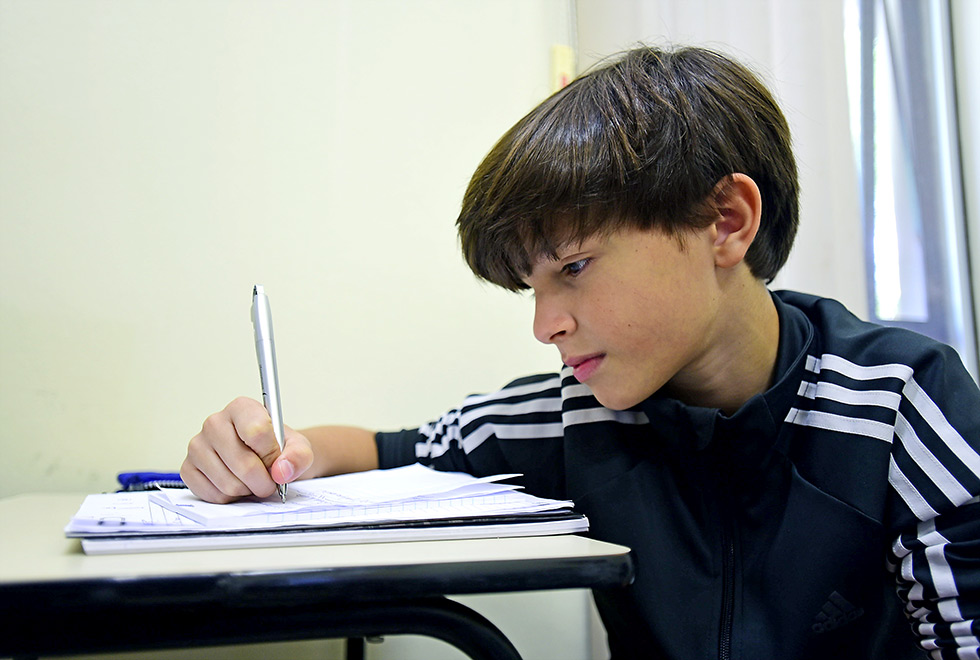 menino debruçado sobre o caderno