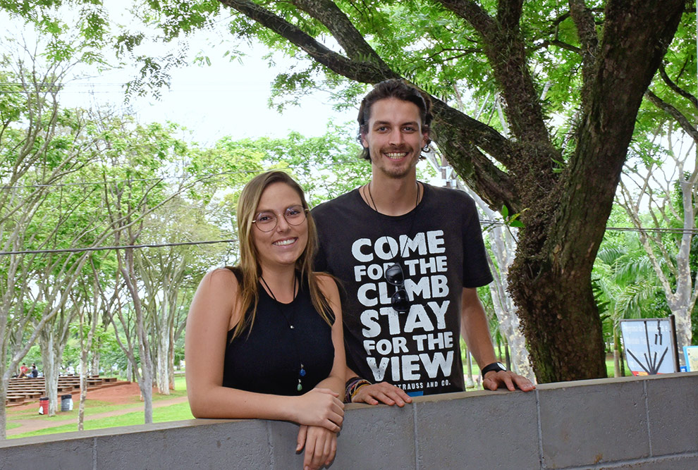 Bruna e Higor em pé, atrás de uma mureta, sorrindo para a foto