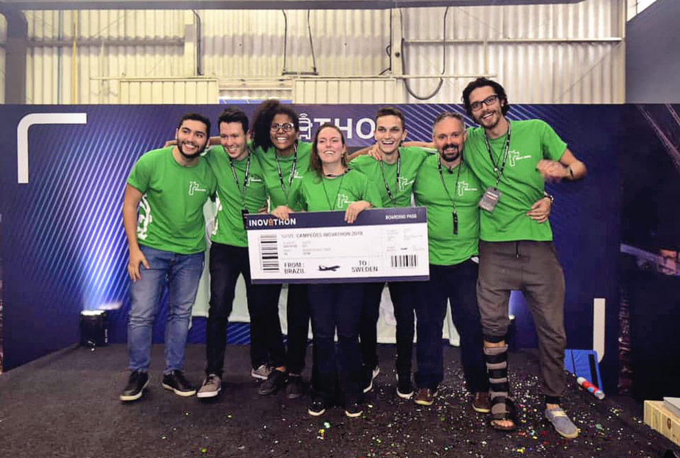 Equipe campeã segura um tíquete de passagem aérea gigante como premio do Inovathon