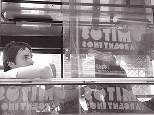 Cartaz de um bar de rock refletido em janelas de um ônibus