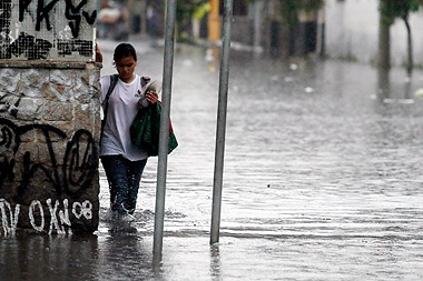 Pedestre em rua próxima à marginal Tietê passa por ponto de alagamento provocado por chuva que atingiu São Paulo na última semana de novembro: ocupação desordenada de leitos de rios agrava problema (Foto: Antoninho Perri)