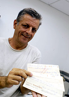 O professor Edson Moschim exibe os cheques entregues por Lattes ao barbeiro: erros no preenchimento