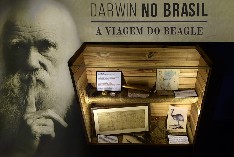 Exposição Darwin no Brasil,na Biblioteca Central Foto montagem que mostra uma das caixas da exposição e detalhes do cartaz. O rosto de Darquin está em destaque e ao lado o título da exposição