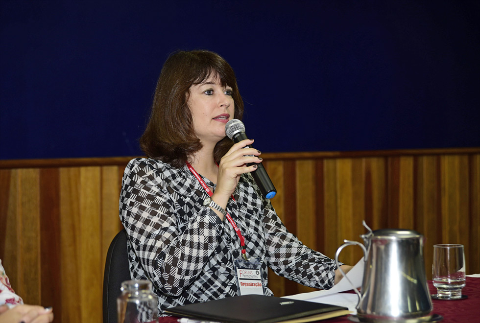Kelly Cristina Brandão da Silva, professora do DDHR e organizadora do evento mulher fala ao microfone senta à mesa