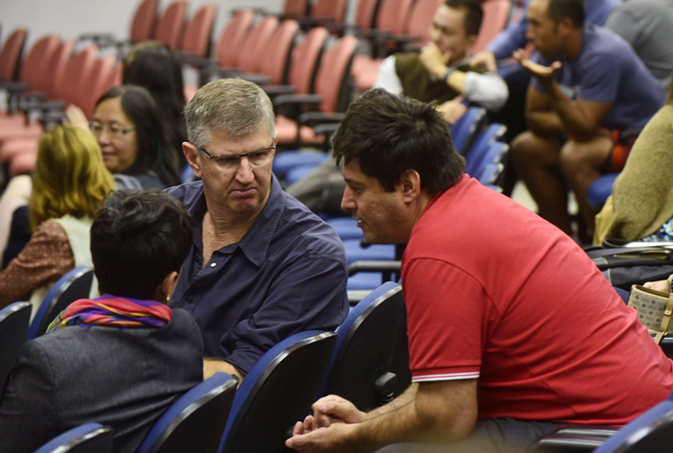 tres pessoas sentadas em auditorio conversam