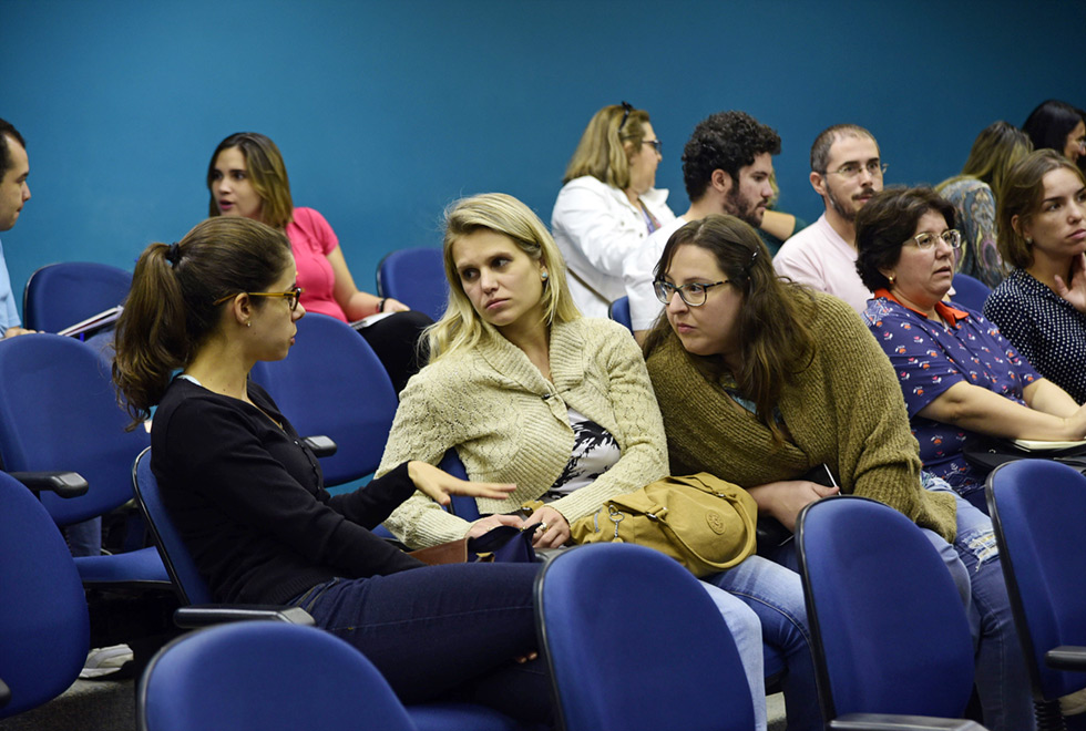 três mulheres sentadas em auditorio conversam