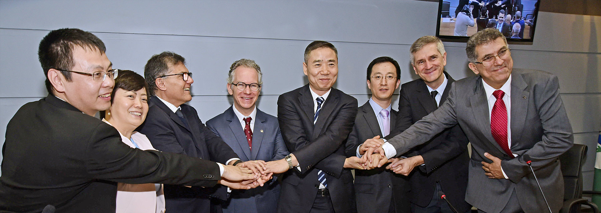 Foto mostra delegação chinesa dando as mãos, formando uma corrente de cooperação com membros da reitoria, entre eles o reitor Marcelo Knobel, ao centro