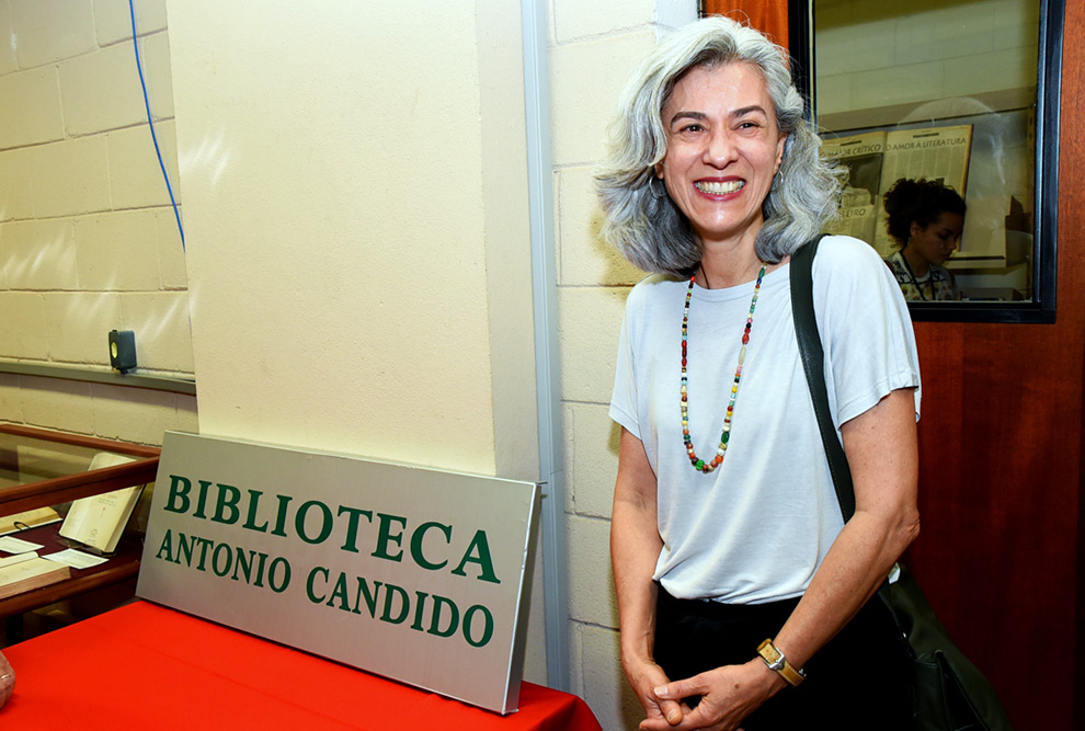 Marina, filha do homenageado, ao lado da placa da Biblioteca Antonio Candido