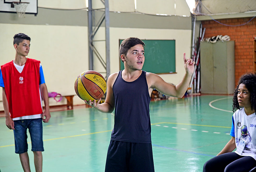 O monitor Laércio dando início a partida de basquete adaptado, está em pé com a bola nas mãos