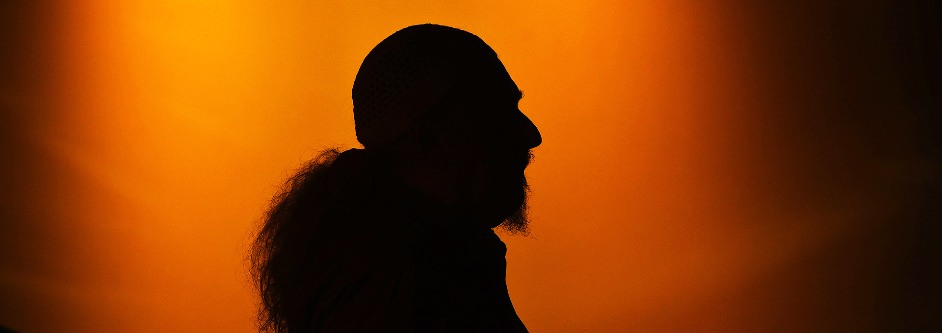 Egberto Gismonti deixa o palco do Instituto CPFL, dia 21, na abertura do V Festival de Música Contemporânea Brasileira, no qual foi homenageado | Foto: Antonio Scarpinetti Audiodescrição: Imagem em perfil e de busto, homem em acentuada contraluz radial e em tom laranja, onde aparece apenas o contorno da pessoa fotografada. Imagem 1 de 1.