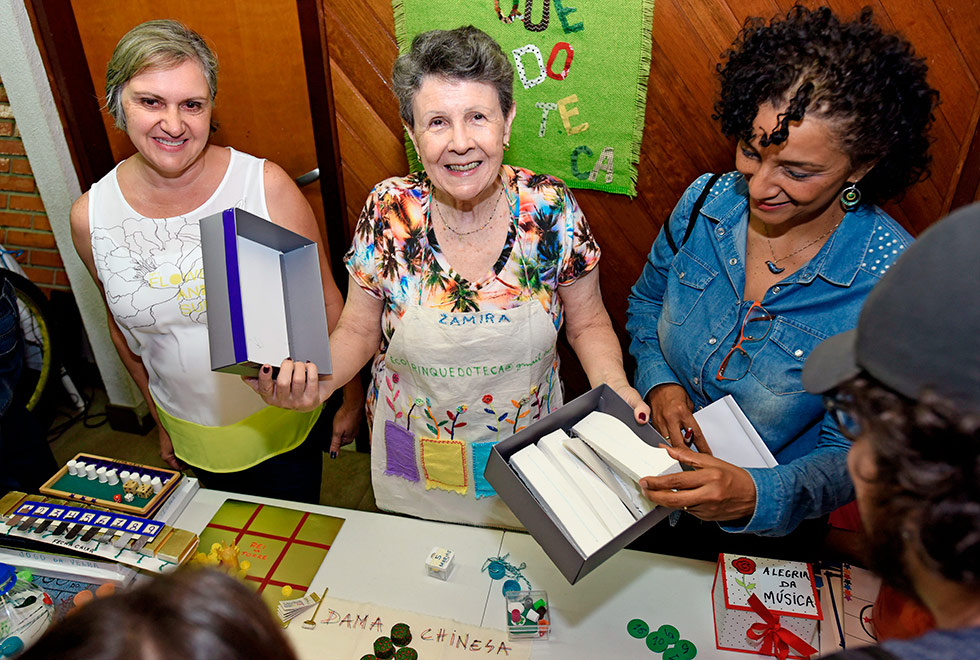 Zamira (ao centro) e os brinquedos Zamira e mais duas integrantes da ONG mostram os jogos