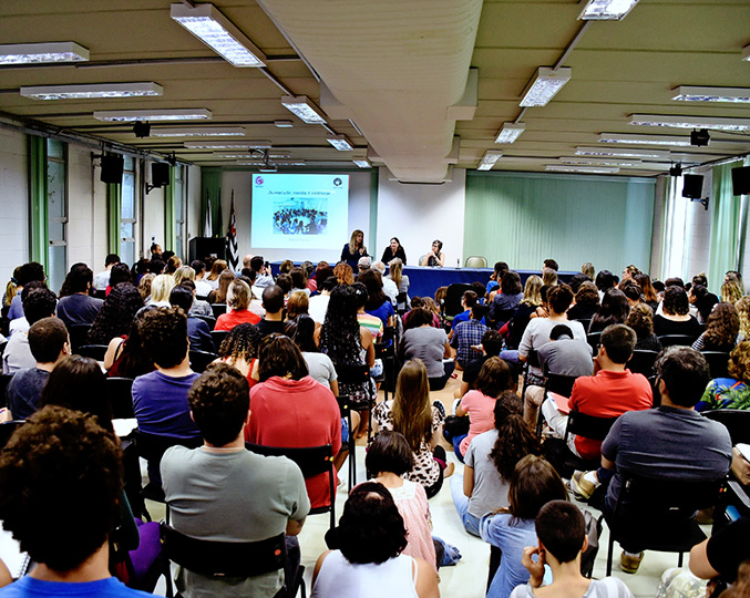 Evento na Faculdade de Educação, um mês após massacre em Suzano Várias pessoas estão sentadas, algumas no chão, para assistir o debate