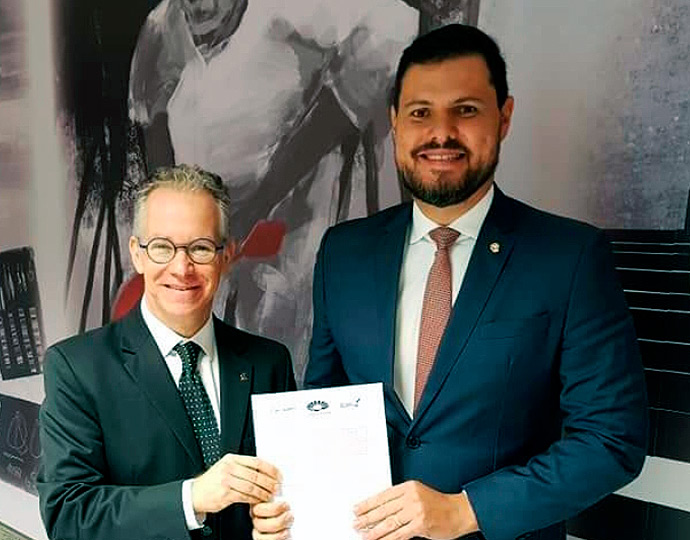 Marcelo Knobel e o presidente da ANPT seguram o documento e sorriem para a câmera