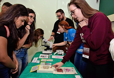 No microscópio, alunos visualizam lâminas contendo bactérias da boca No microscópio, alunos visualizam lâminas contendo bactérias da boca