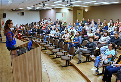 Imagem mostra palestrante em frente a plateia no auditório do GGBS