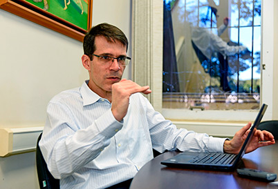 O pró-reitor de Desenvolvimento Universitário, professor Chico Professor Chico está sentado em frente a um laptop em seu gabinete