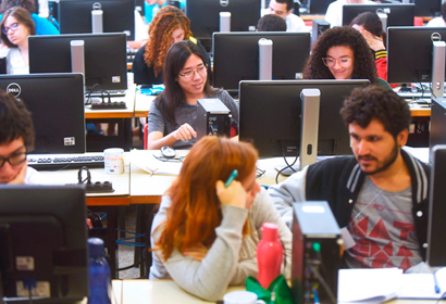 audiodescrição: fotografia colorida mostra sala cheia com muitos jovens estudantes em frente a computadores.