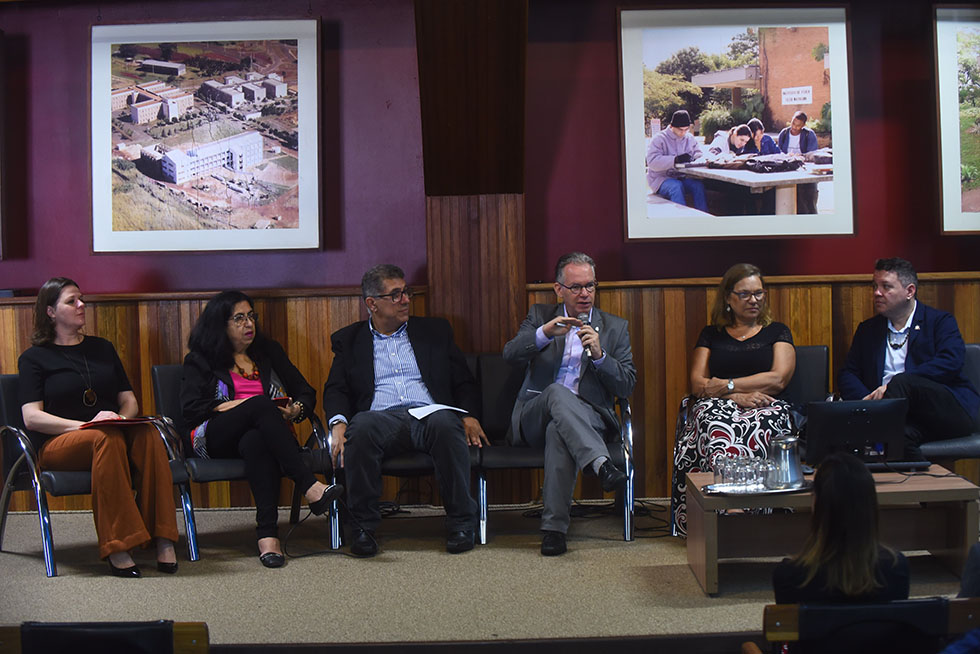 audiodescrição: fotografia colorida mostra representantes do banco santander, da unicamp, da ufpa sentados no palco do auditório do centro de convenções da unicamp durante abertura do programa ciência e arte povos da amazônia. São três mulheres e três homens e o reitor da Unicamp, Marcelo Knobel, está com o microfone na mão falando à plateia. 