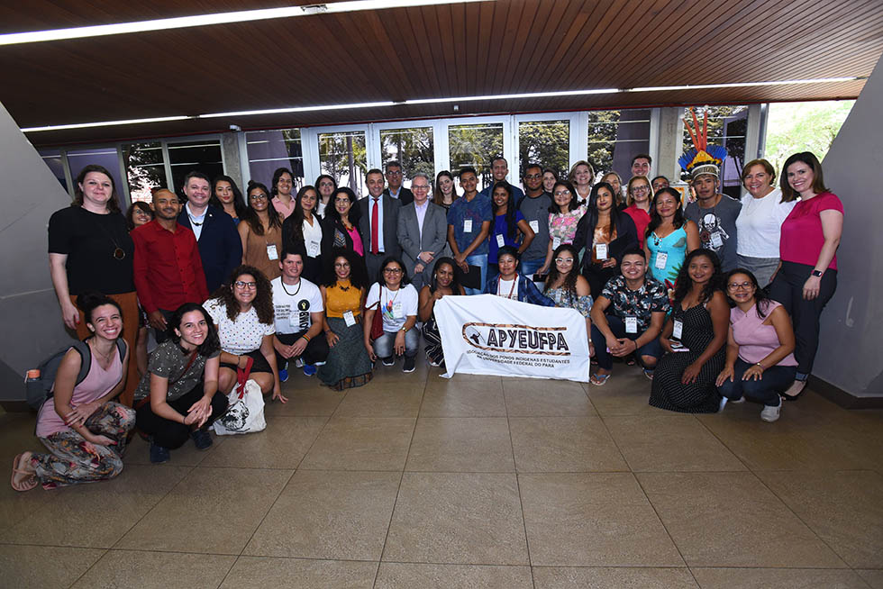 Foto coletiva após abertura do programa Ciência e Arte Povos da Amazônia audiodescrição: fotografia colorida cerca de 40 pessoas estão na foto, a maioria são jovens, estudantes indígenas, quilombolas e ribeirinhos e extrativistas da universidade federal do pará. também encontra-se o reitor da unicamp, pró-reitores da Unicamp e da universidade do pará e representantes do banco santander. alguns estão abaixados na foto, na primeira fileira, e seguram uma bandeira dos povos indígenas da universidade federal do pará.