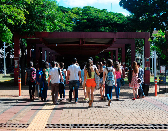 Foto mostra grupo de alunos de costas, andando em direção ao Restaurante Universitário da Unicamp. Tecle entrer para acessar.