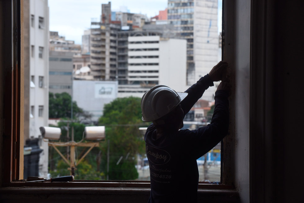 Obras iniciaram em fevereiro audiodescrição: fotografia colorida mostra trabalhador, de costas, trabalhando em uma janela janela