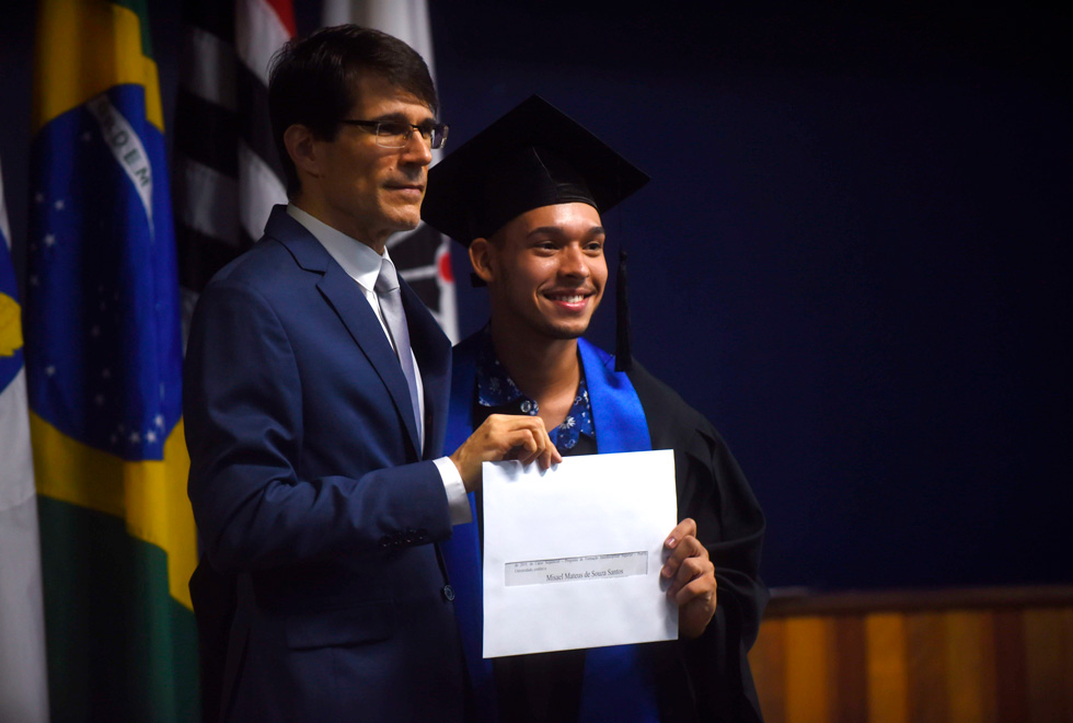 foto mostra aluno recebendo certificado do paraninfo