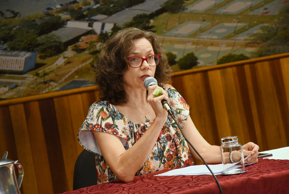 foto mostra a professora Daniela Gatti com o microfone nas mãos falando