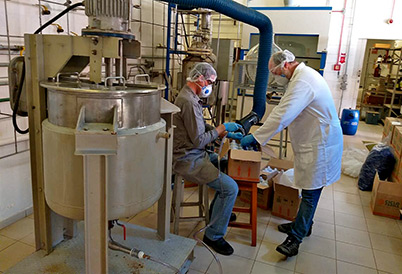 Doação de 1.250 litros deve ser aprovada pela empresa até sexta-feira (27); IQ vai produzir álcool em gel foto mostra uma máquina de envase de álcool em primeiro plano e, em segundo plano, dois pesquisadores, vestidos com roupas de proteção, manuseando as garrafas