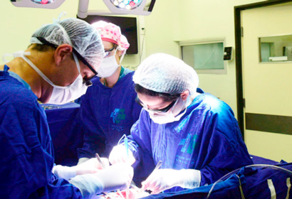 Cirurgia é feita para controlar ou diminuir o número de crises epilépticas e melhora qualidade de vida da criança Audiodescrição: três profissionais realizando cirurgia