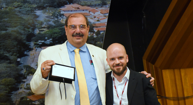 "Universidade pública é muito boa, mas precisa gerar sucessores", afirma Luiz Roberto Curi foto mostra o presidente do conselho nacional de educação e o professor marcelo mori. O presidente segura uma placa de homenagem