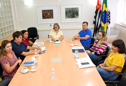 Audiodescrição: fotografia colorida mostra mesa de reunião com membros do comitê da proteção da dados da Unicamp