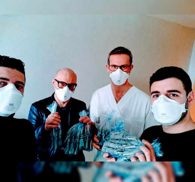 Equipe da startup italiana Isinnova mostra válvulas produzidas com uma impressora 3D para hospitais Quatro homens usando máscaras e com materiais desenvolvidos